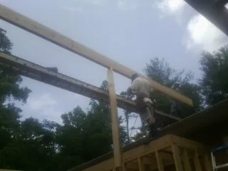 Carpenter setting a ridge beam over a new addition frame — Ice Dam Removal by Roofing Brothers in Potterville
