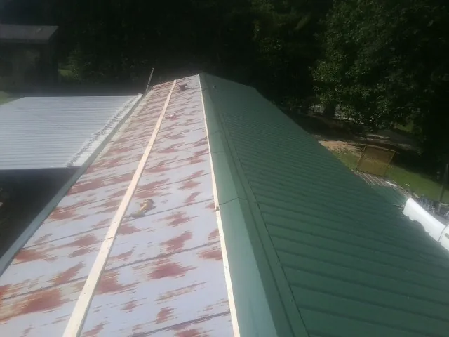 Old rusted panels beside newly installed green metal roofing — Wind Damage Roof Repair by Roofing Brothers in Potterville