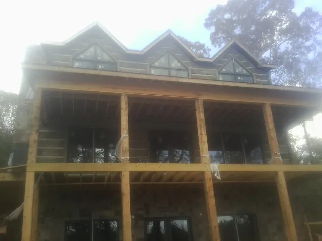 Dormers and porch framing on a large log home under construction — Roof Coating work by our crew in Potterville