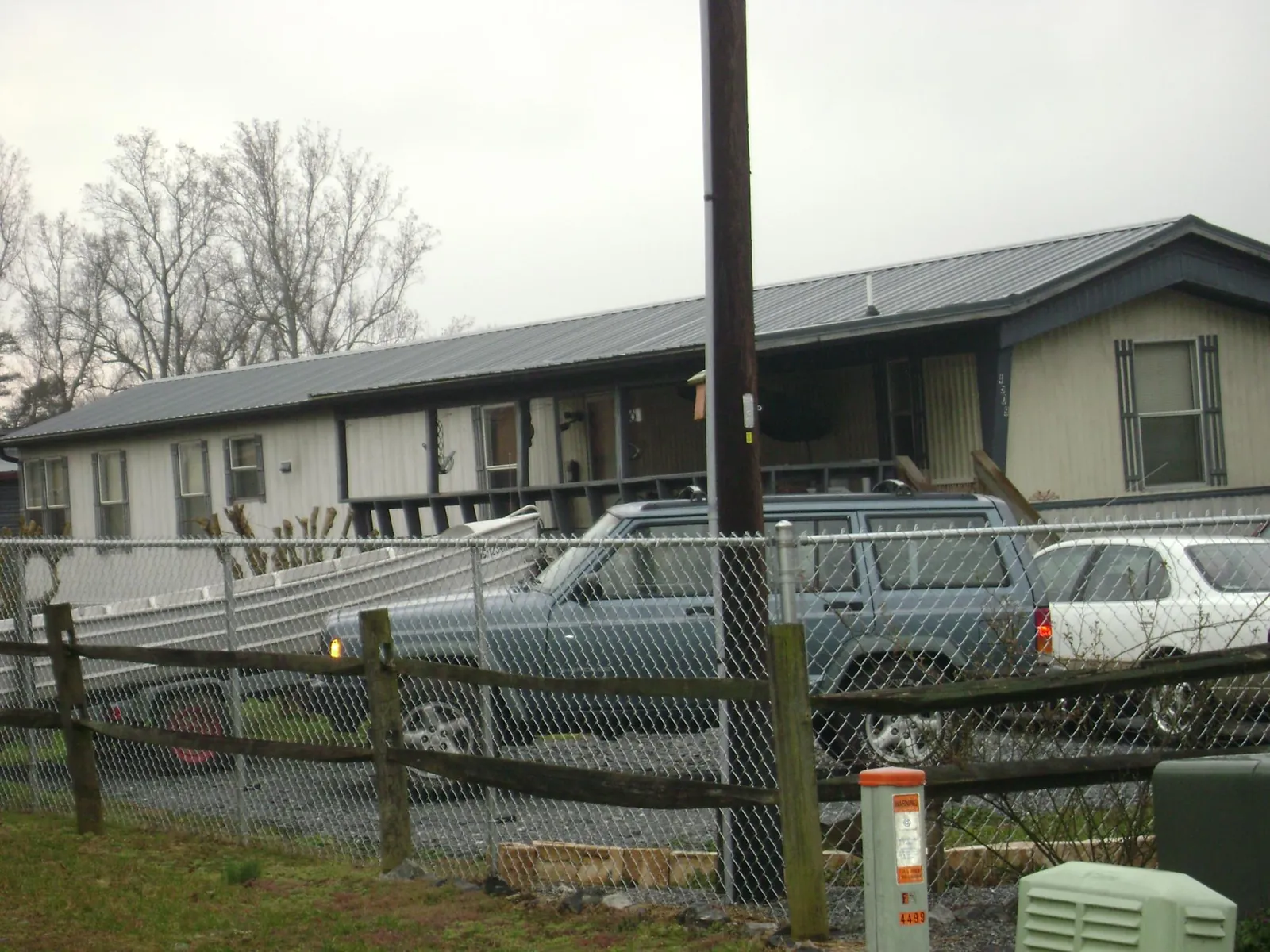 Dark metal roof on a long single story building behind a chain link fence in Potterville