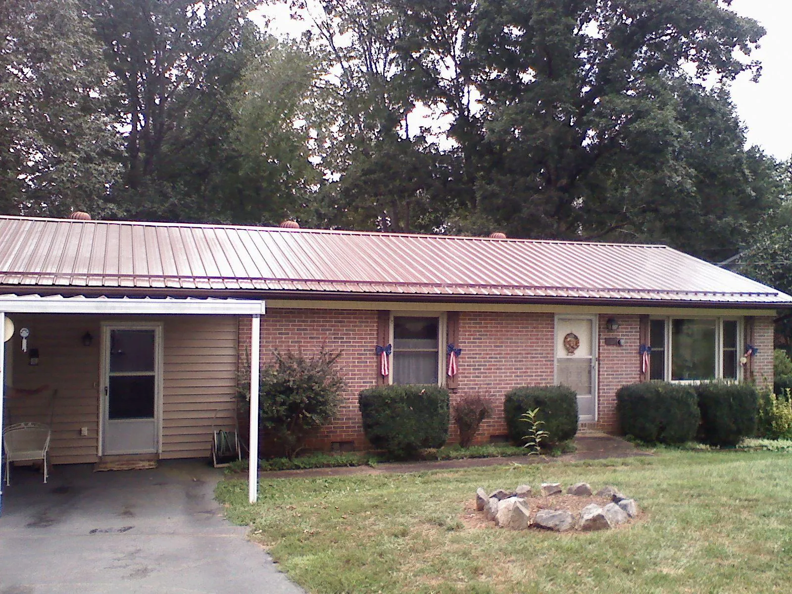Bronze metal roof and carport on a brick ranch home — Roof Repair work by our crew in Potterville