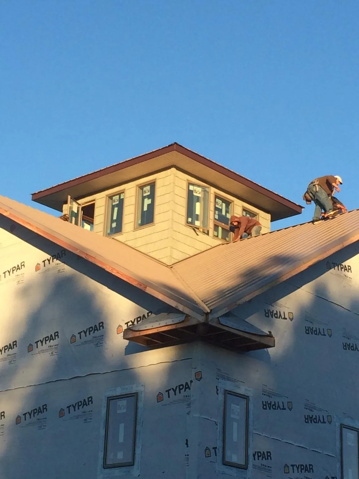 Roofers working around a rooftop cupola on a new metal roof at sunset — Roof Waterproofing in Potterville by Roofing Brothers